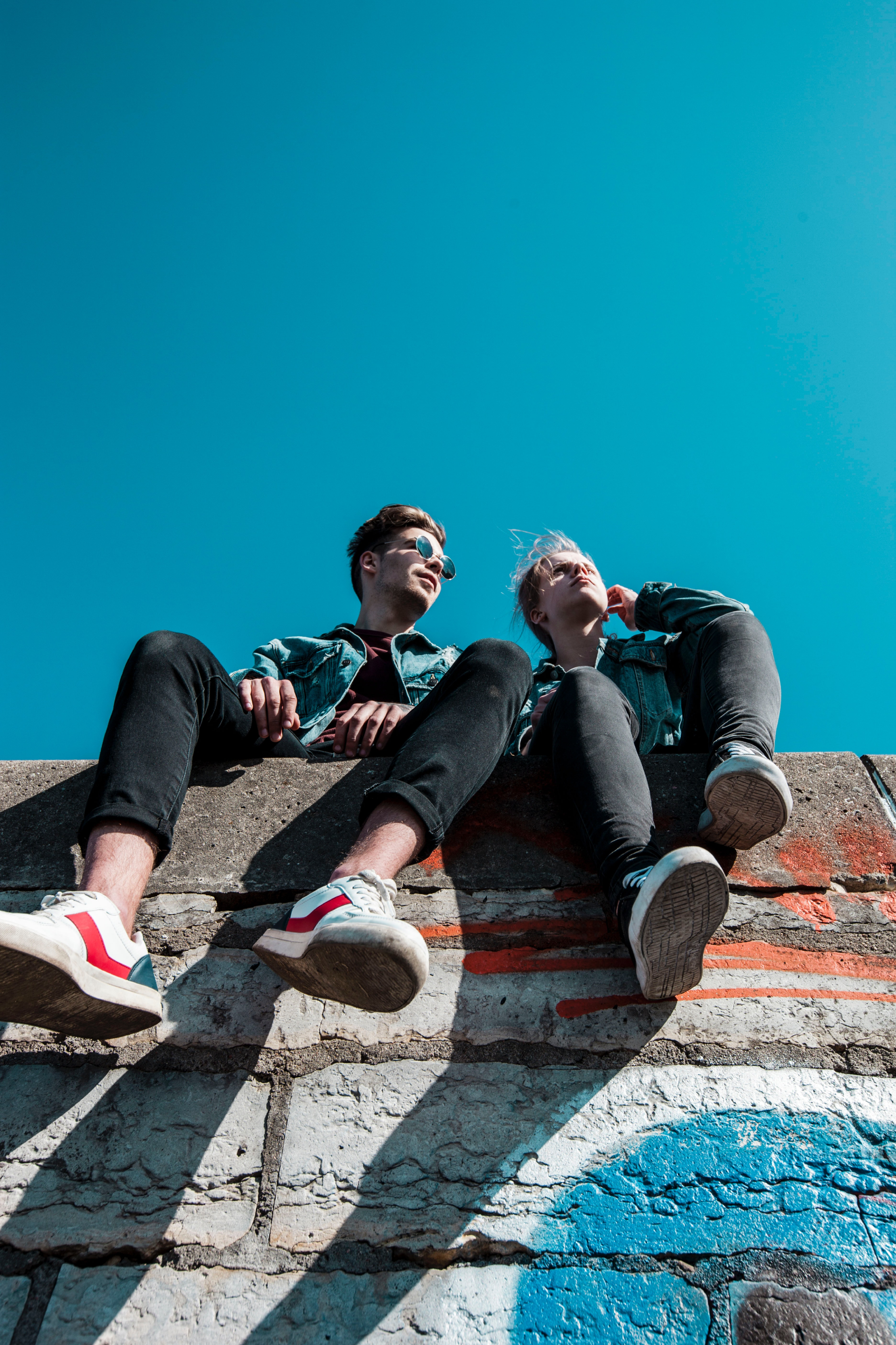 two young people sitting on a wall